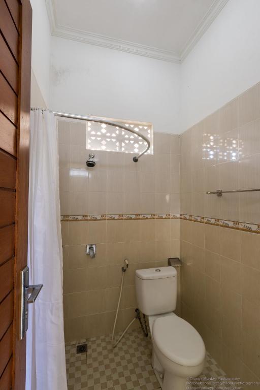 a bathroom with a toilet and a shower curtain at Sudiana House in Ubud