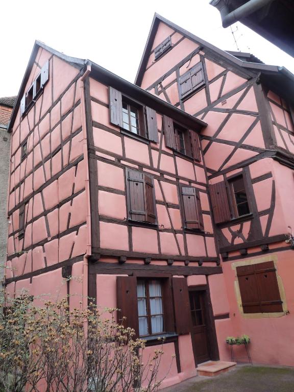 un bâtiment rose avec des fenêtres et des portes dans l'établissement Baribal'ele, à Colmar