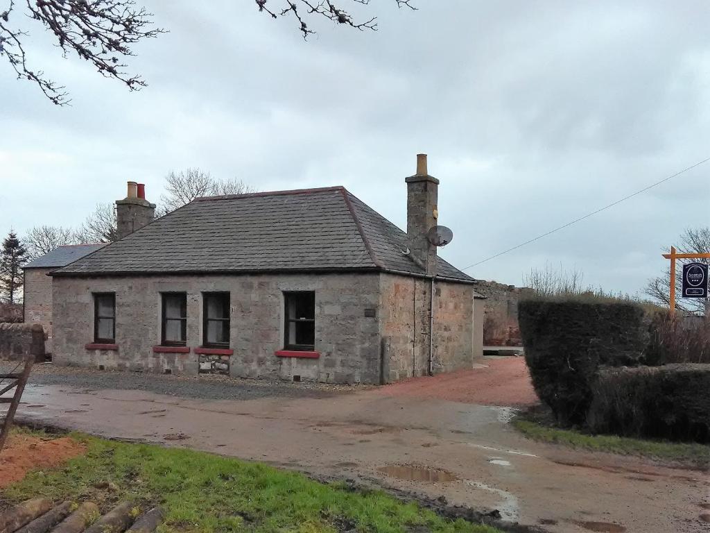 an old stone house with two chimneys on top of it at Berryhill Cottages in Peterhead