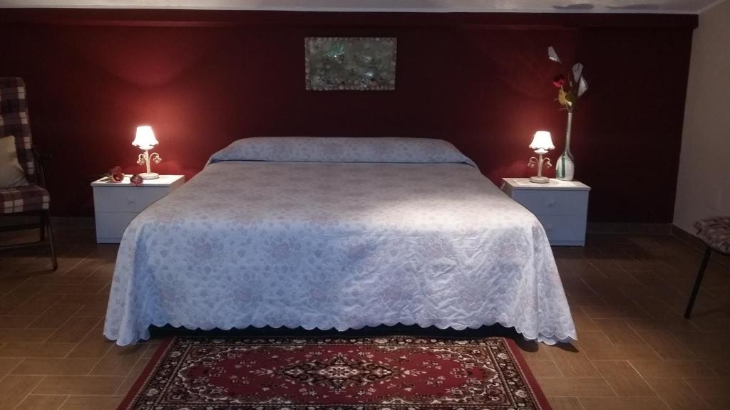 Etna Sun Guest House في ماسكالي: غرفة نوم بسرير كبير مع مواقف ليلتين