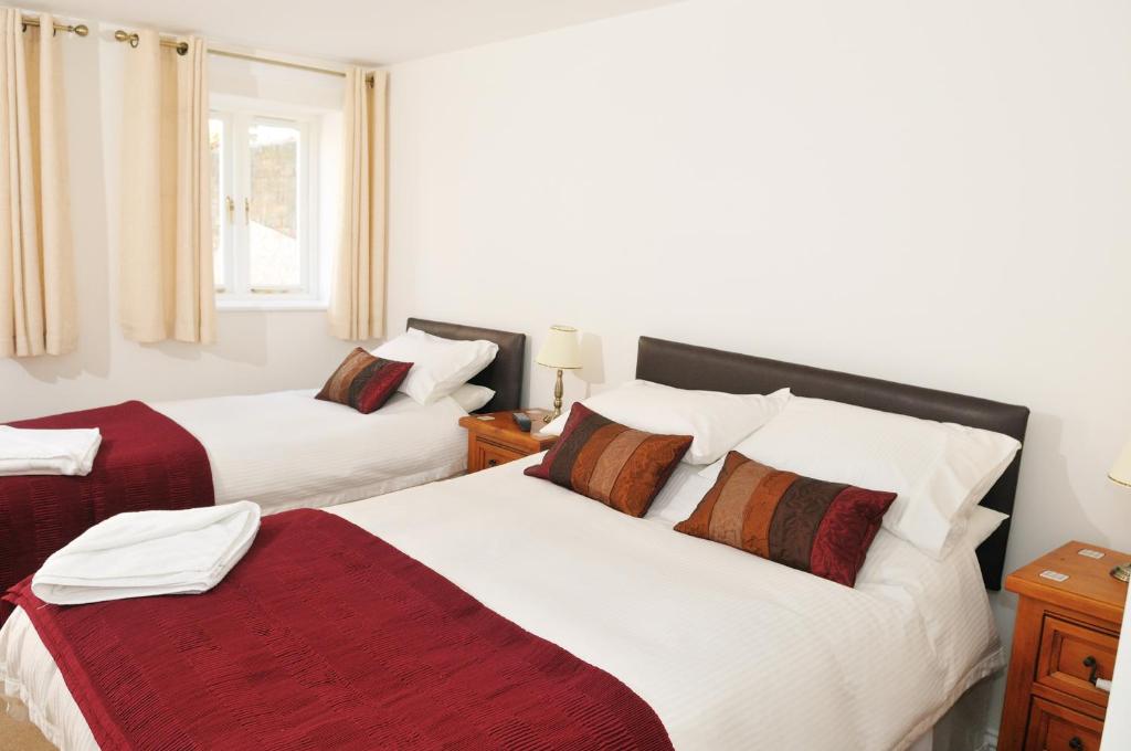 a bedroom with two beds with white and red sheets at Balmoral Guest House in Darlington