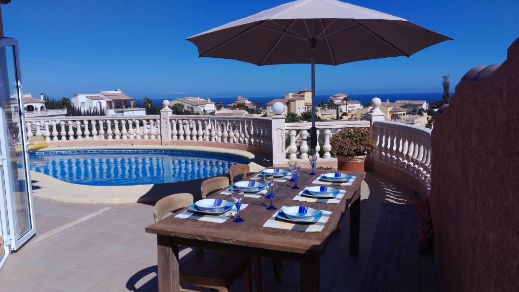 einen Holztisch mit Sonnenschirm auf dem Balkon in der Unterkunft Villa Magnolias in Benitatxell