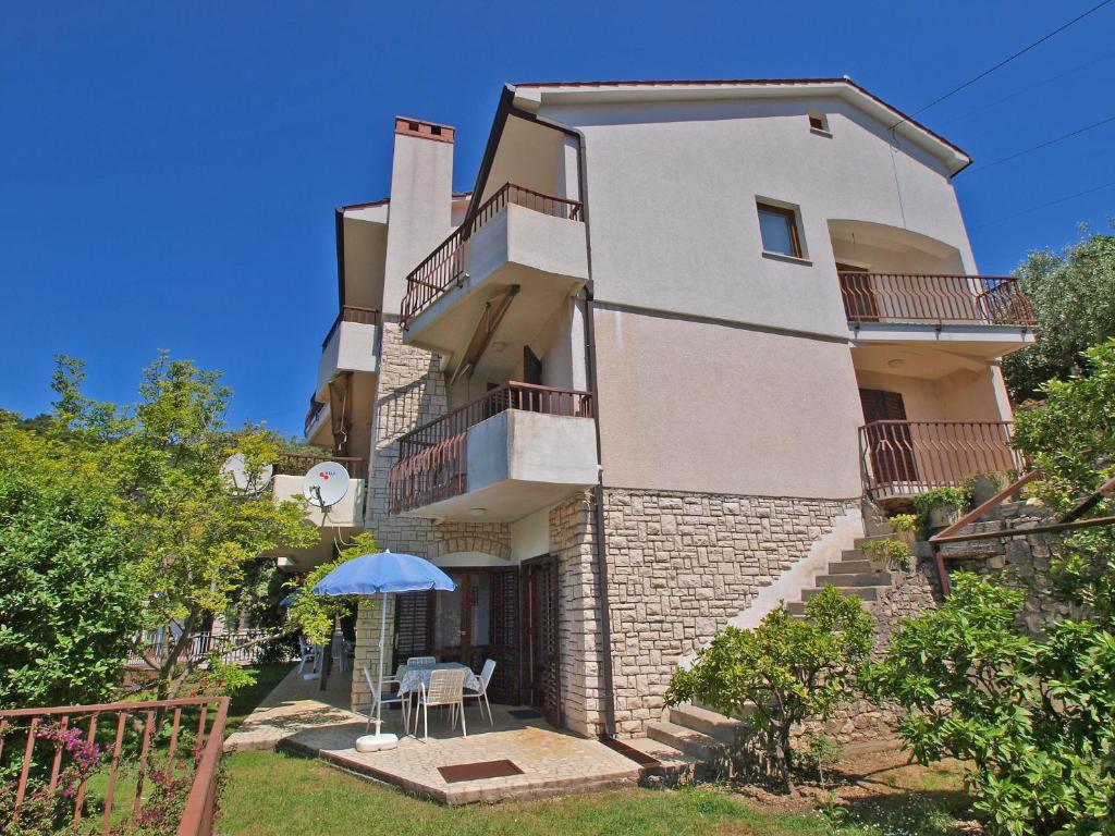 a large white building with a table and an umbrella at Apartments Jolanda 911 in Rabac