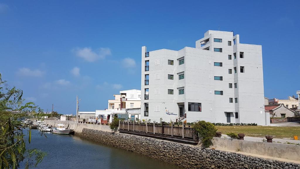 un edificio blanco junto a un río con barcos dentro en 逸遊蔚境民宿, en Magong