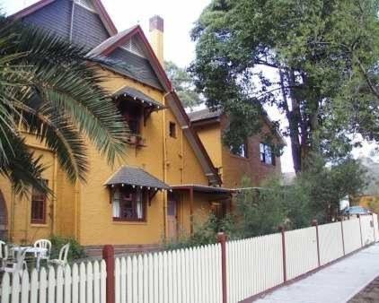 una casa amarilla con una valla delante de ella en Burwood Bed and Breakfast, en Sídney