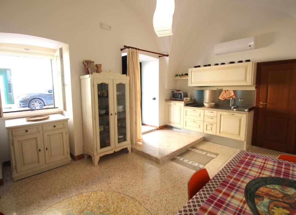 una cocina con armarios blancos y una ventana en Corte di Pietra, en Ruffano