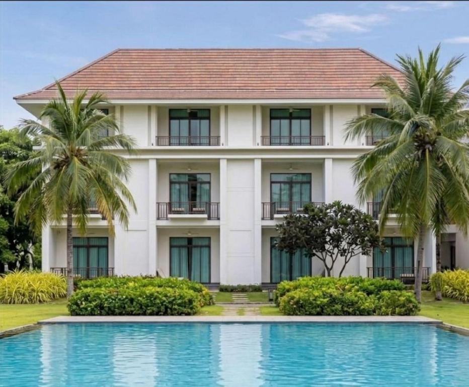 A swimming pool in front of a palm-lined hotel building.