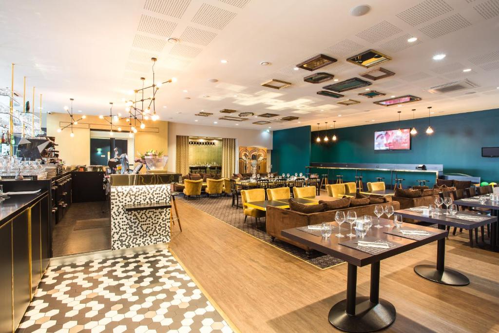een restaurant met tafels en stoelen en een bar bij Hotel Gatsby by HappyCulture in Chassieu