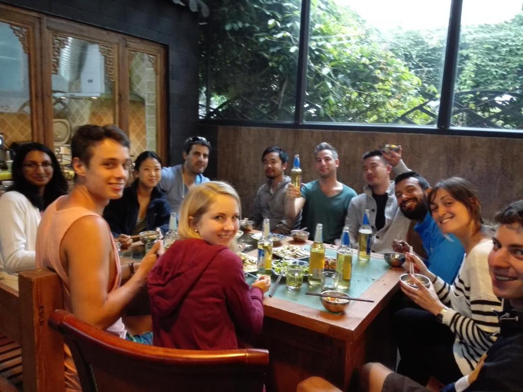 a group of people sitting around a table in a restaurant at Mama Naxi Guesthouse in Lijiang