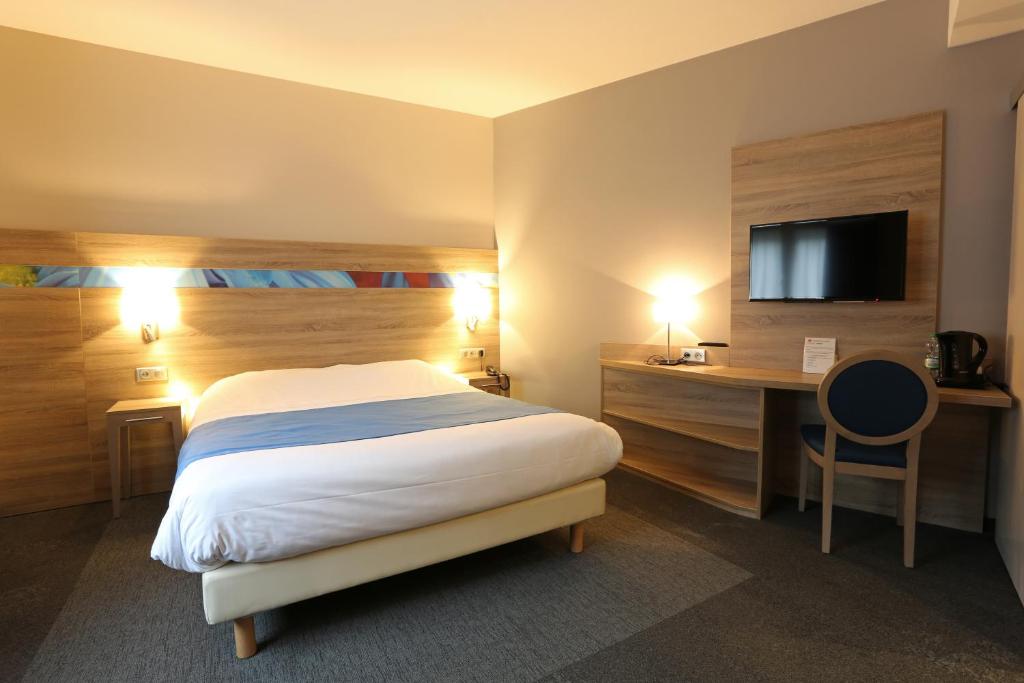 a hotel room with a bed and a desk and a tv at Hotel Restaurant Le Coquelicot in Burnhaupt-le-Haut
