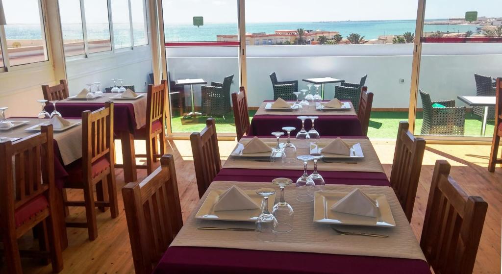 un restaurante con mesas y sillas y vistas al océano en Boutique Hôtel Albaraka, en Dakhla