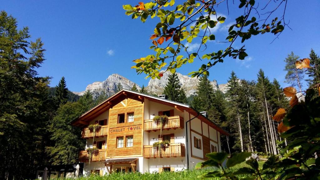 a building with a balcony and mountains in the background at Chalet Tovel - Mountain Lake in Tuenno