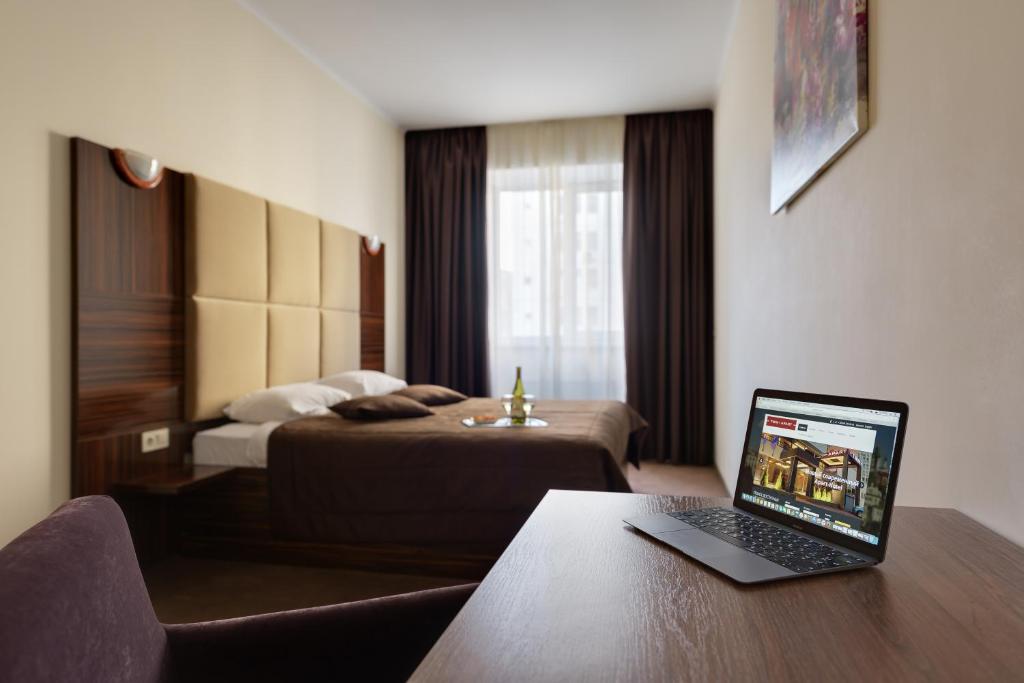 1 dormitorio con cama y mesa con ordenador portátil en Twin Apart Hotel, en Kiev