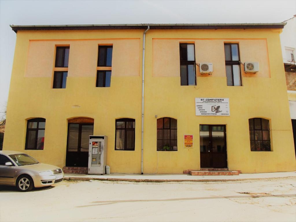 żółty budynek z samochodem zaparkowanym przed nim w obiekcie House for Guests and Friends w mieście Swisztow