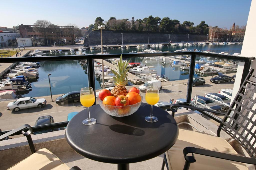 a table with a bowl of fruit and two glasses of wine at Lipotica Luxury Accommodation in Zadar