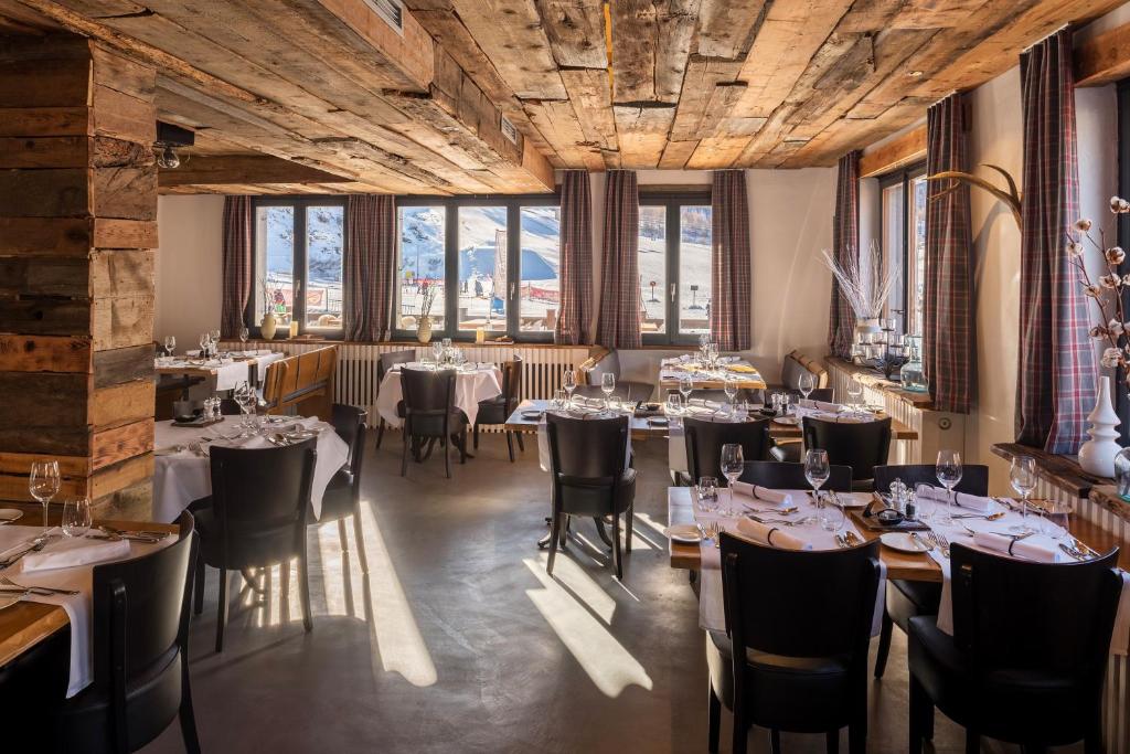 a restaurant with tables and chairs in a room with windows at Hotel THE LARIX ski-in ski-out in Saas-Fee