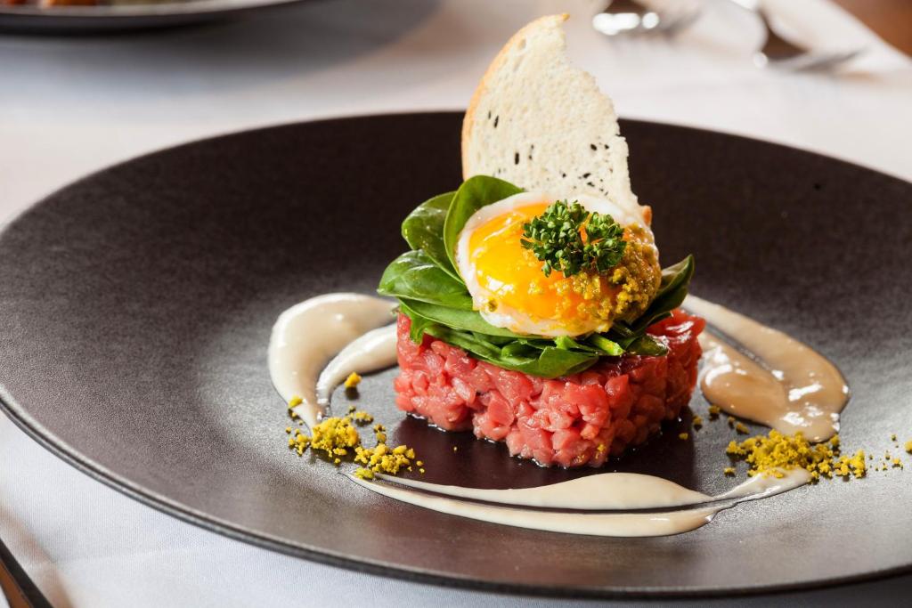 a plate with a sandwich with an egg on it at Hotel THE LARIX ski-in ski-out in Saas-Fee