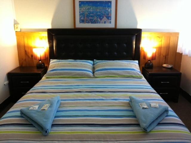 a bedroom with a bed with two pillows on it at Aquarius Motel in Belmont