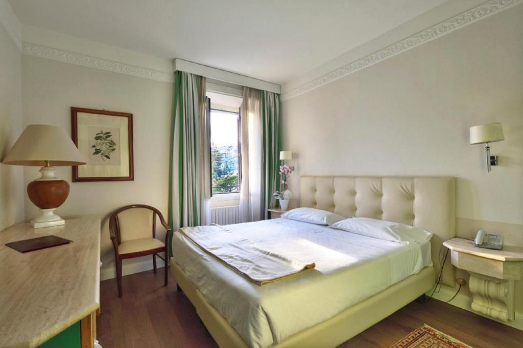 sypialnia z dużym łóżkiem i oknem w obiekcie Lolli Palace Hotel w San Remo