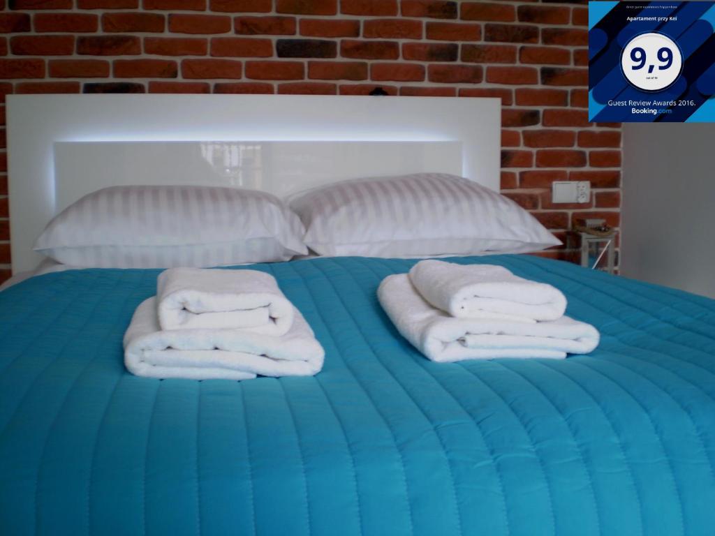 a blue bed with towels on top of it at M&A Apartament przy Kei in Gdańsk