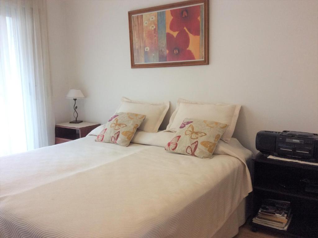 Una cama con sábanas blancas y almohadas en un dormitorio en Borges Intimo en Buenos Aires