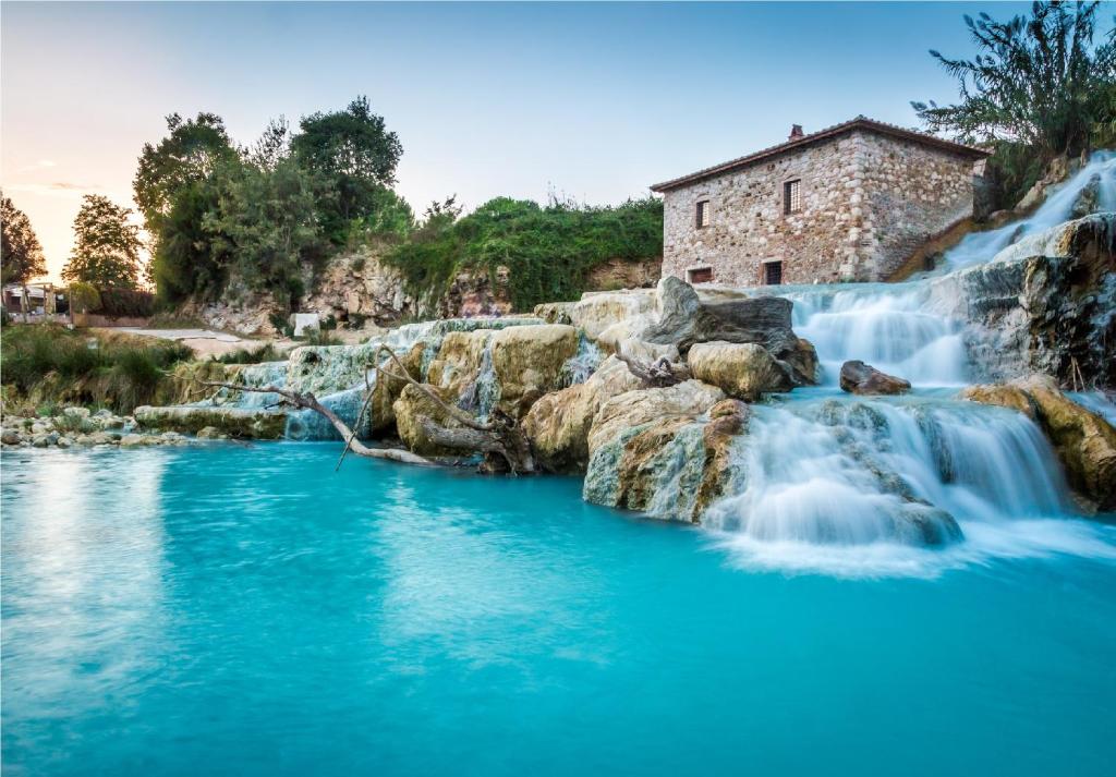 a river with a waterfall in front of a building at Agriturismo Le Cascatelle in Saturnia
