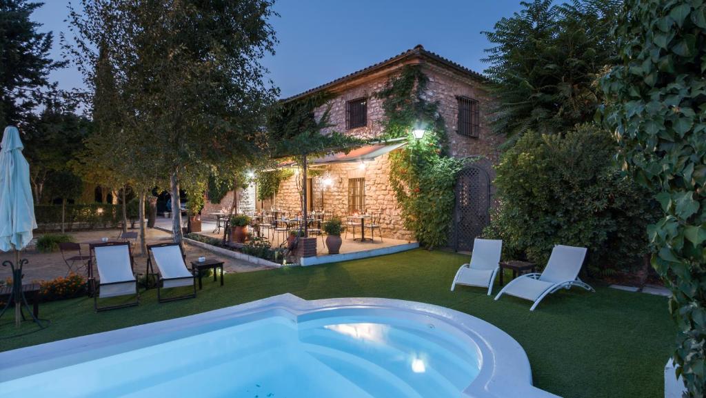 a backyard with a hot tub and chairs and a building at La Caseria de Tito in Úbeda