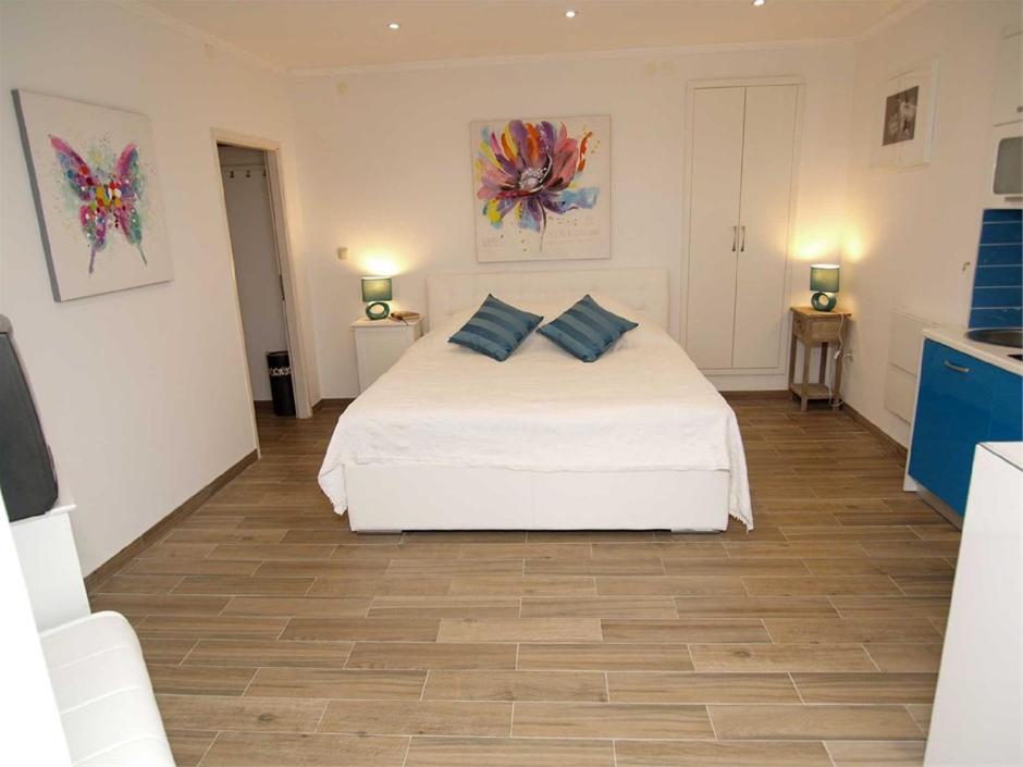a bedroom with a white bed with blue pillows on it at Studio Lorena in Mali Lošinj