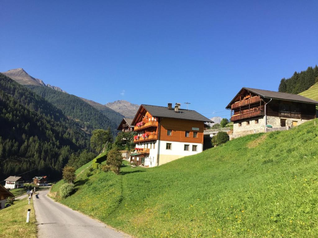 a house on a hill next to a road at Ferienwohnungen Böhm in Sankt Jakob in Defereggen