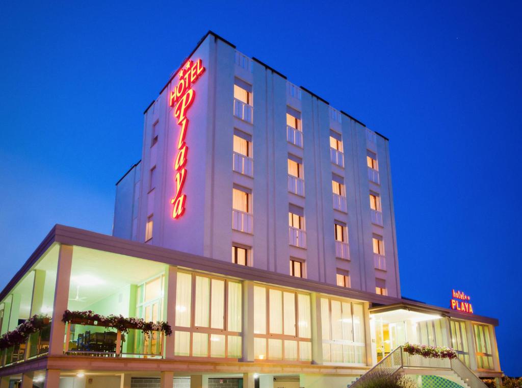 un edificio alto con un'insegna al neon di Hotel Playa a Bibione