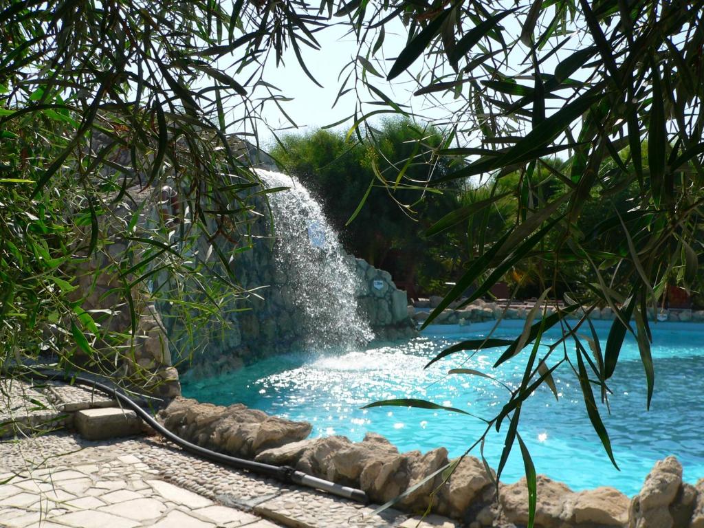 a waterfall in the middle of a swimming pool at Riviera Beach Bungalows in Kyrenia