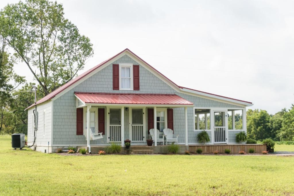 una casa con dos sillas blancas en el césped en The Little Farmhouse Sleeps 6, en Columbia