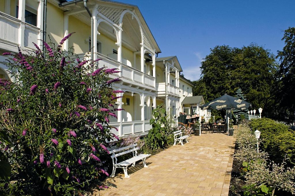 a large white building with purple flowers and benches at Wald-Hotel in Ostseebad Sellin