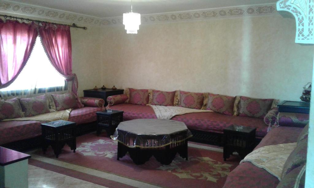 sala de estar con sofá rojo y mesa en Appartement Chham, en Marrakech