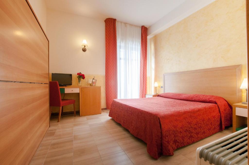 ein Hotelzimmer mit einem roten Bett und einem Schreibtisch in der Unterkunft Park Hotel Villa Americana in Rodi Garganico