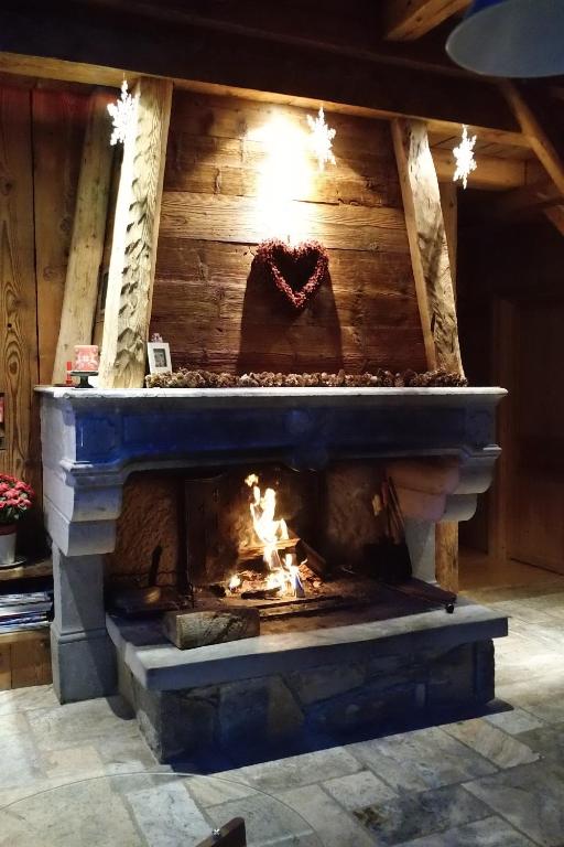 a stone fireplace with a fire in it at Chambre d'Hôtes La ferme d'en bas in Samoëns