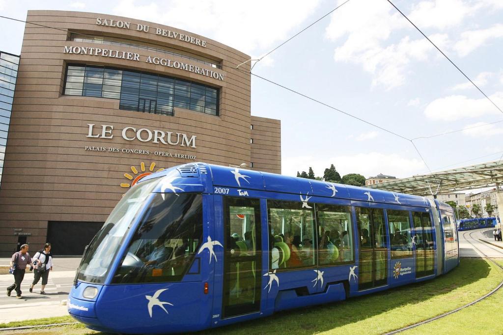 a blue train is parked in front of a building at Hôtel Ulysse Montpellier Centre in Montpellier