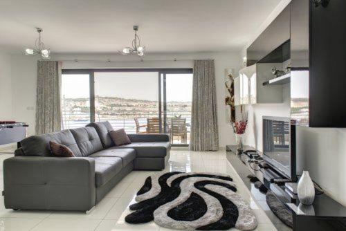 a living room with a couch and a television at Water's Edge Apartment in St Paul's Bay