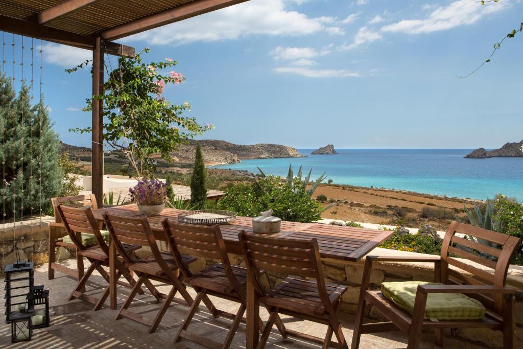 a table and chairs on a patio with a view of the ocean at Natica Mare Villas in Xerokampos