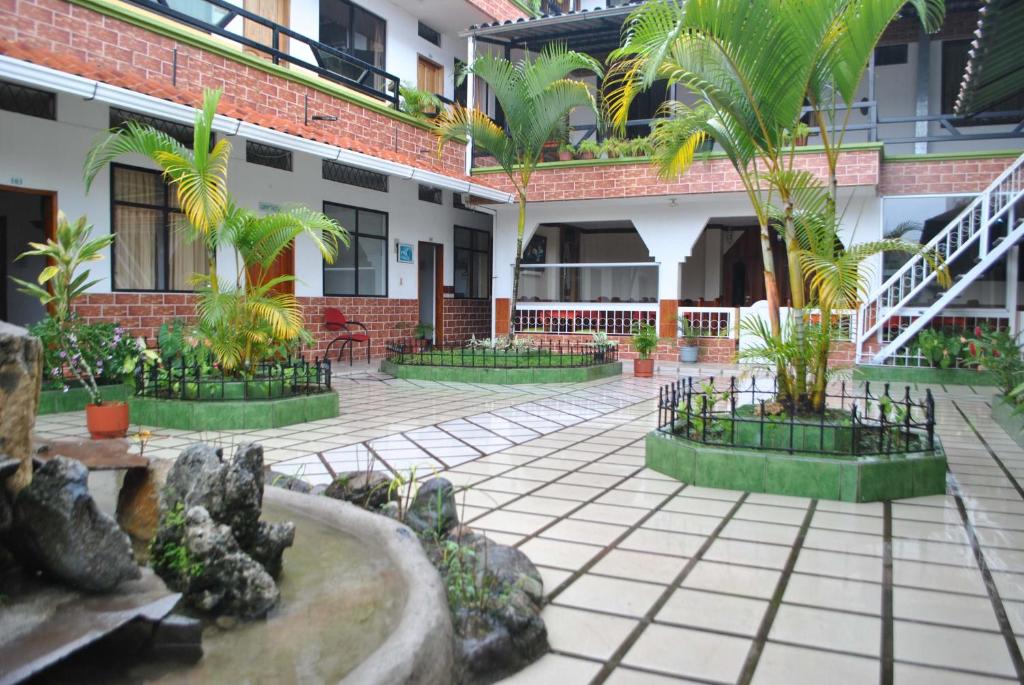 un patio con palmeras frente a un edificio en Palmar del Rio Gran Hotel, en Archidona