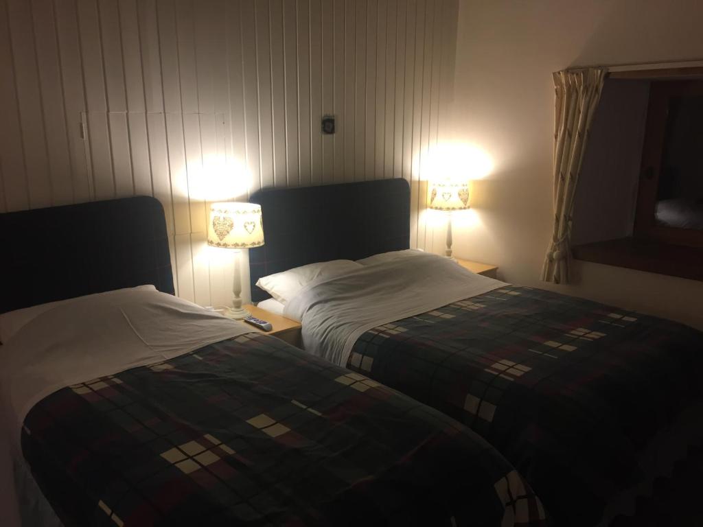 twee bedden in een hotelkamer met twee lampen bij Hillview Cottage in Stirling