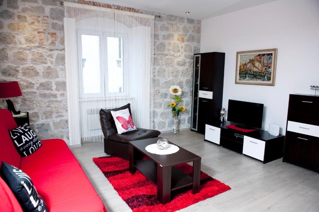 ein Wohnzimmer mit einem roten Sofa und einem TV in der Unterkunft Apartman u srcu grada - Ilićev prolaz in Split
