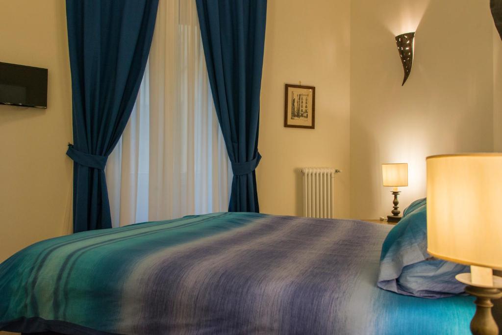 a bedroom with a bed with blue curtains and a window at B&B Univercity in Naples