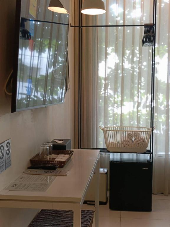 A narrow desk beside a curtained window, with a TV, minibar and simple refreshments.