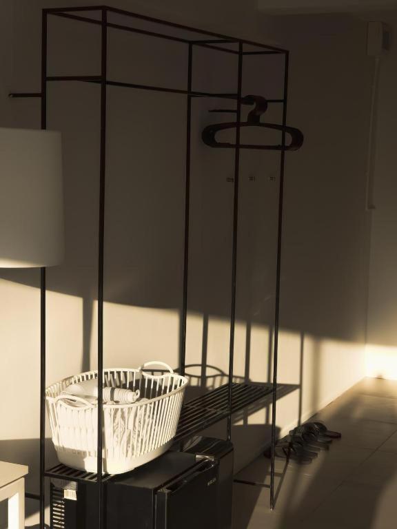 An open black metal wardrobe with baskets, hangers, and a small luggage surface.