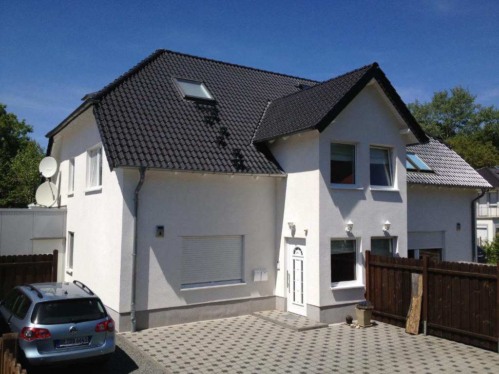 une maison blanche avec une voiture garée devant elle dans l'établissement Ferienwohnung Unikat, à Bad Harzburg