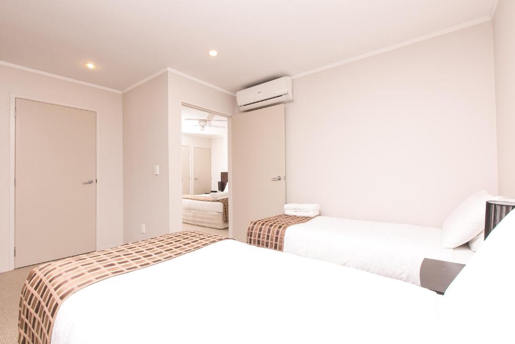 2 camas en una habitación con paredes blancas en Parkview Motor Inn, en Pukekohe East