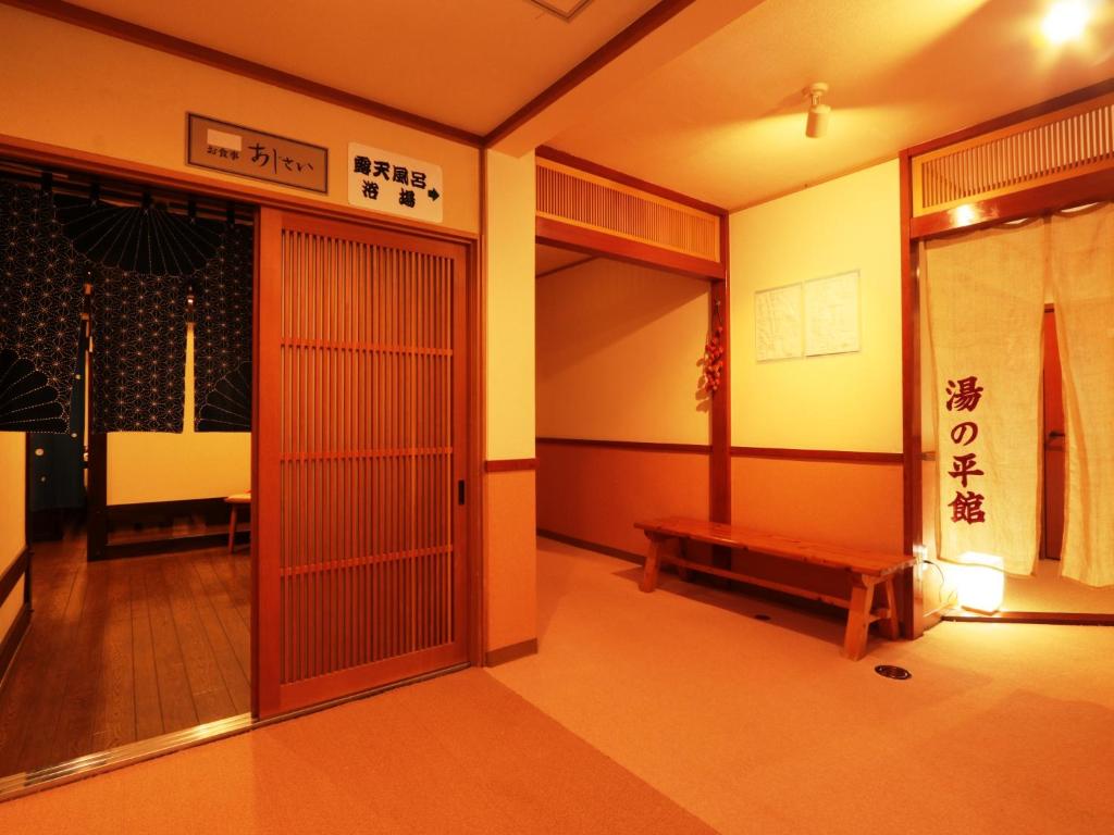 une chambre avec une porte et un banc. dans l'établissement Yunohirakan, à Takayama