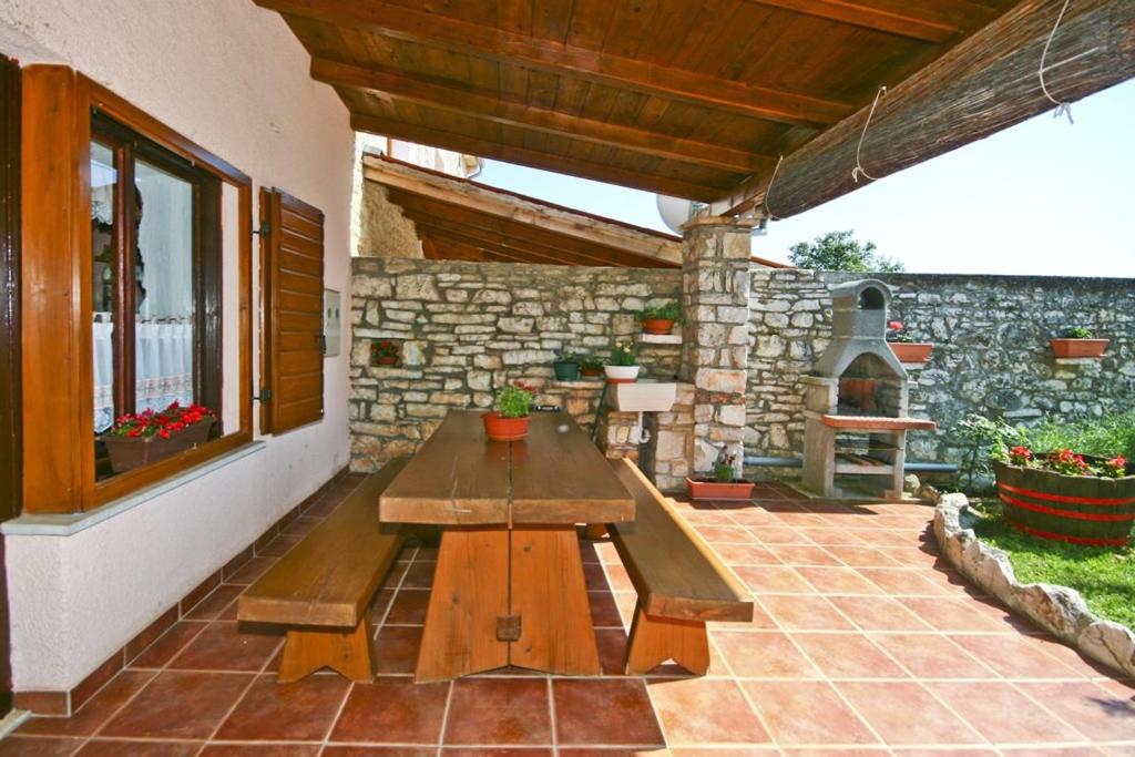 patio z drewnianym stołem i kamienną ścianą w obiekcie Holiday Home Orihi w mieście Barban
