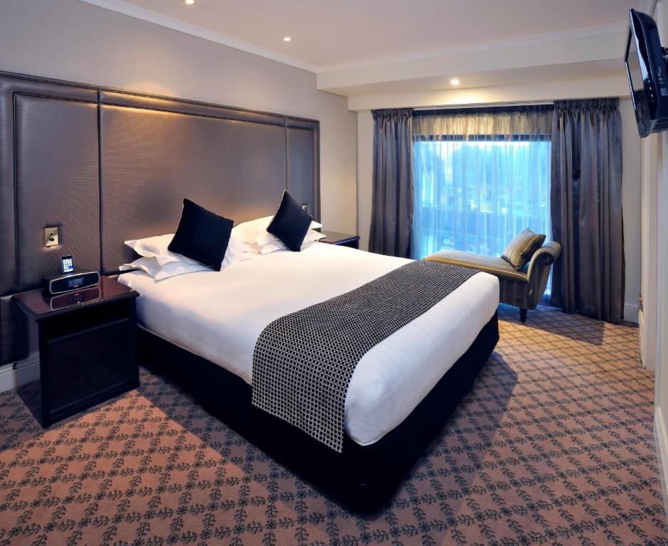 a hotel room with a large bed and a chair at Stamford Plaza Melbourne in Melbourne